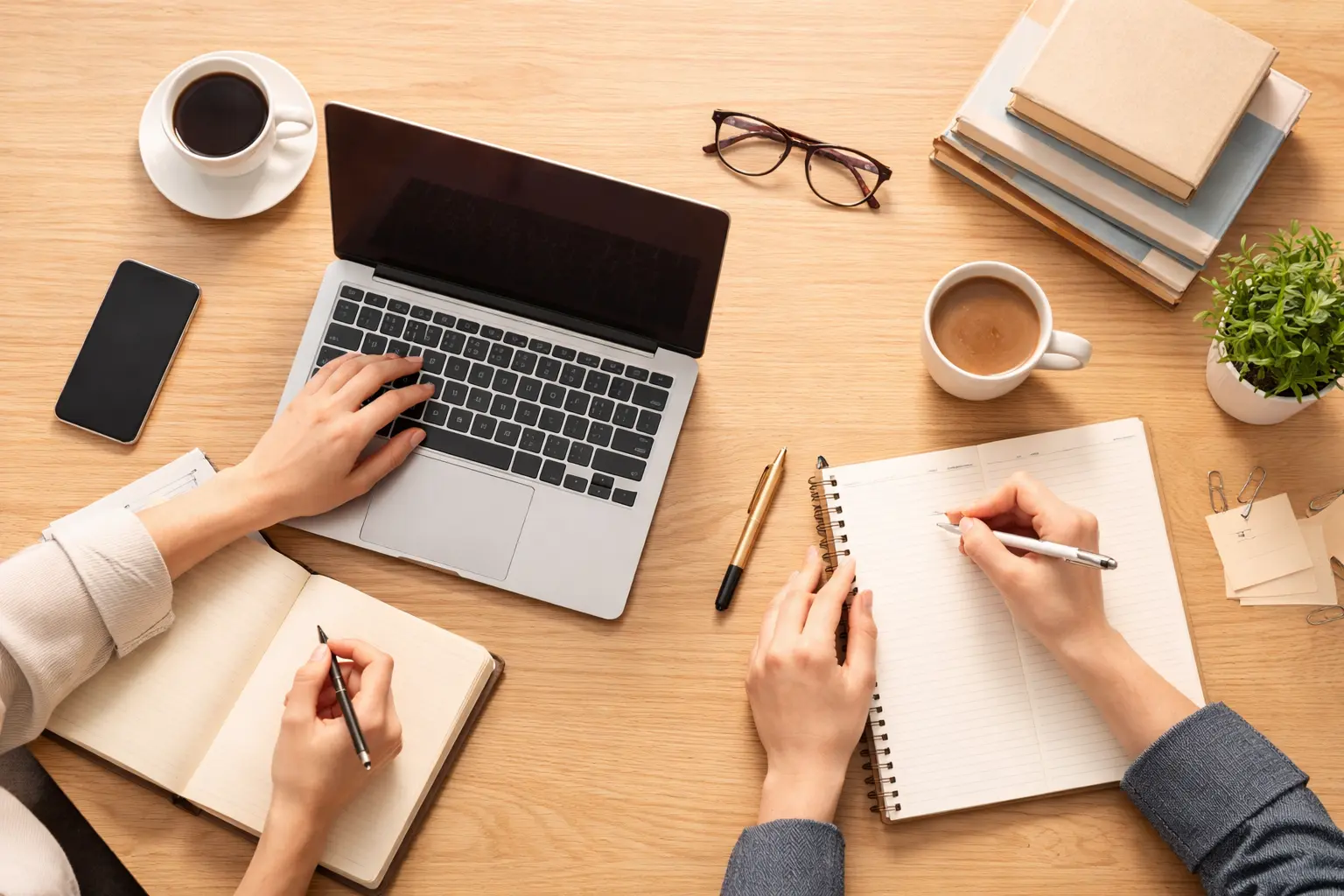 Two people behind the desk with laptop and notebooks